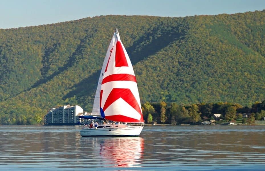 A red and white sailboat glides along the shoreline of Smith Mountain Lake in Virginia