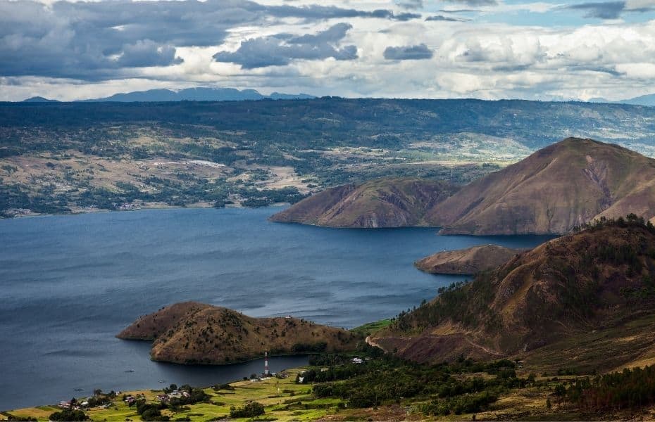 Idyllic view of lake Toba located inside a super volcano with local village, forest, hills and fields.